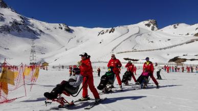 Three people with reduced mobility on a ski slope with their instructors.