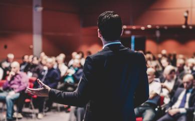 Image of a person during a speech at a presentation.