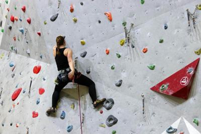 Mujer escalando una pared en rocódromo