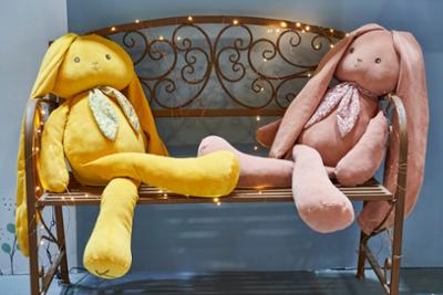 Two cuddly toys sitting on a bench at Intergift