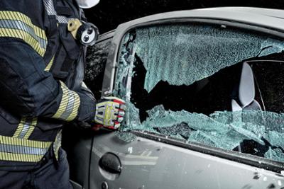 Un operador con guantes uvex interviene en un coche accidentado.