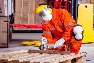 An operator cutting a piece of metal, wearing protective equipment.