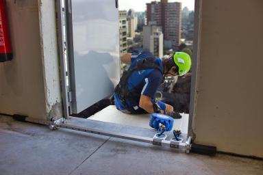 An operator, about to unhook from a building with a jamb anchor device