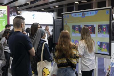 Un stand de SIMO EDUCACION en el un grupo de docentes atiende a las explicaciones sobre una pantalla interactiva