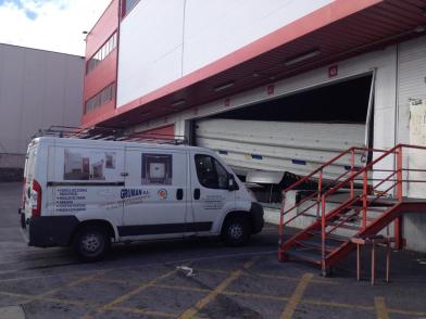 Furgoneta de una empresa de instalación y mantenimiento y puerta automática en una industria