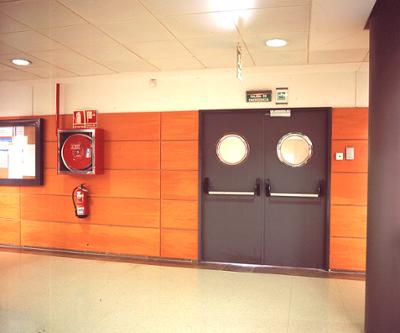 An emergency door next to a fire extinguisher and hose.