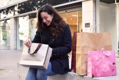 A lady with several shopping bags in front of a shop